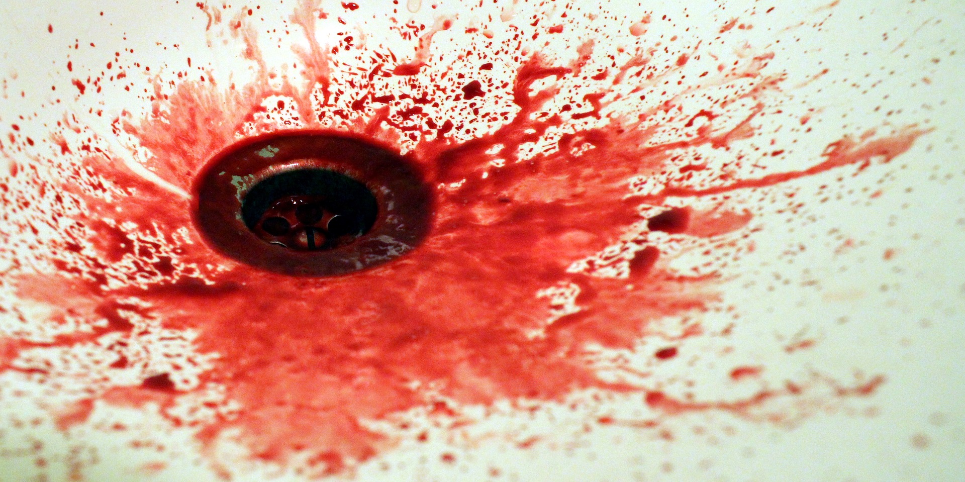 A shower drain with blood splashed around it. Photo.