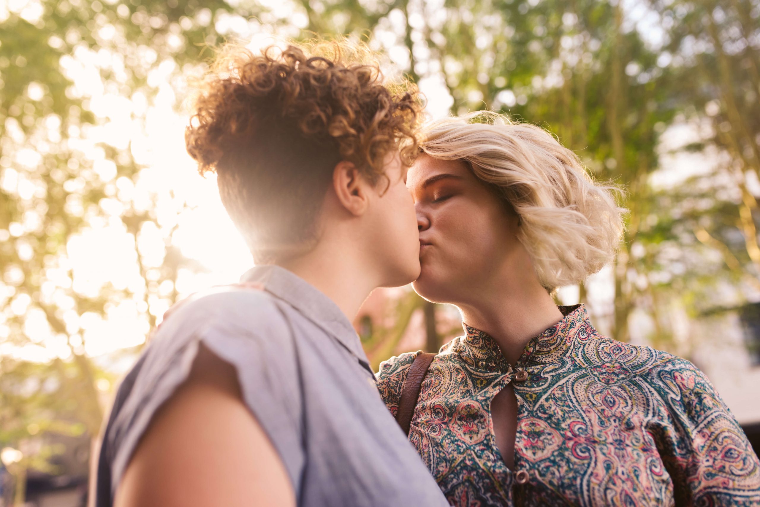 Young lesbian couple kissing each other on a city street. Photo.